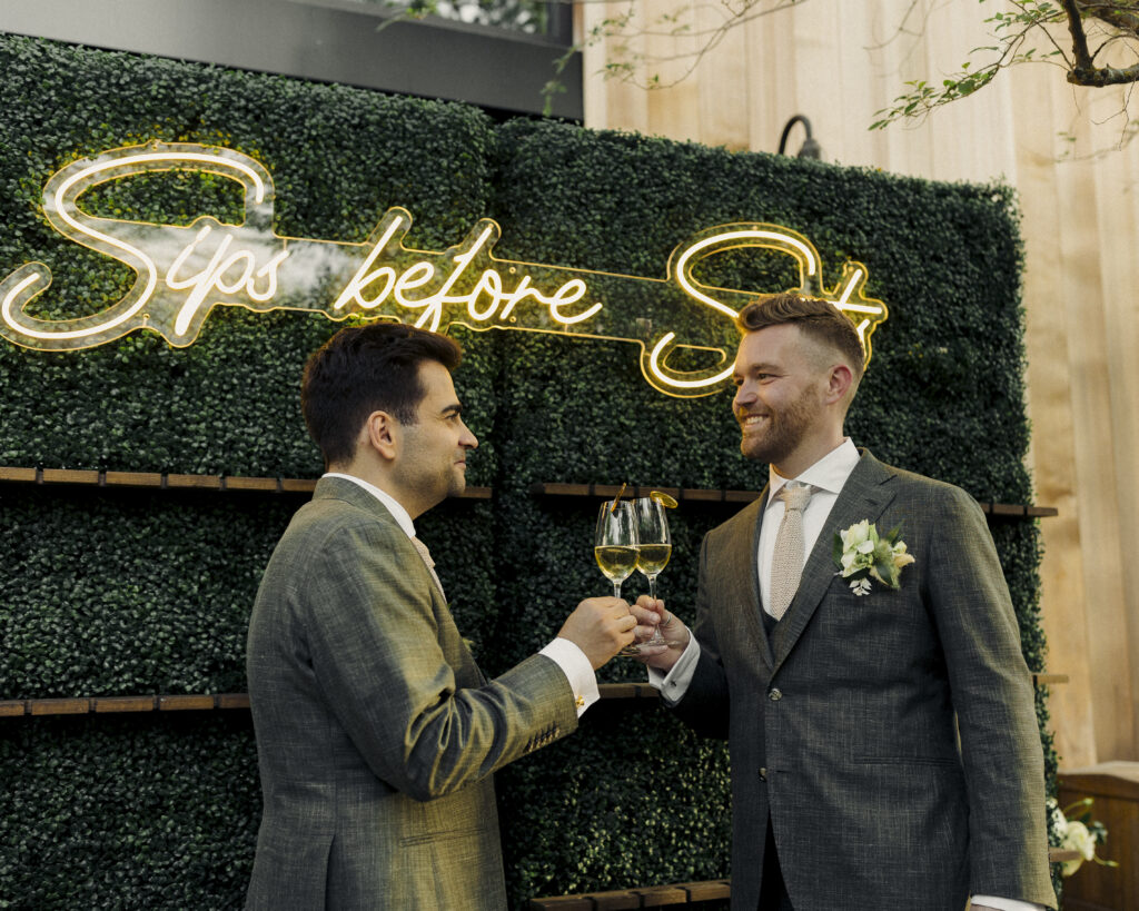 photo of grooms drinking champagne with each other during reception 