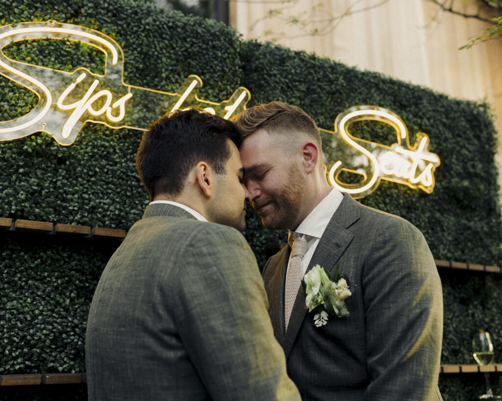 photo of grooms drinking champagne with each other during reception 